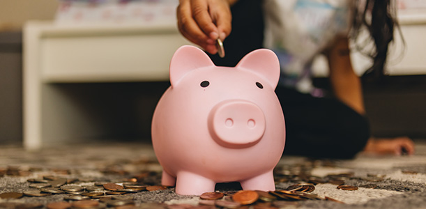 Child puts coins into a piggy bank